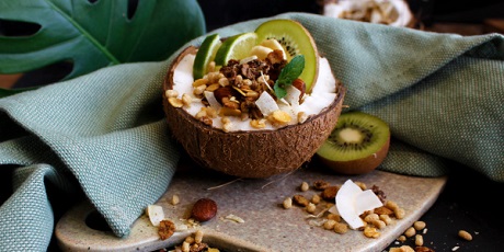 Ciotola di muesli in noce di cocco, decorata con kiwi, lime e menta.