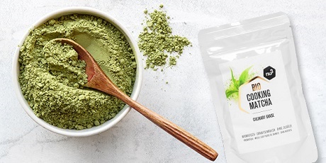 Ciotola con polvere di matcha, cucchiaio di legno e bustina con stampa del prodotto.